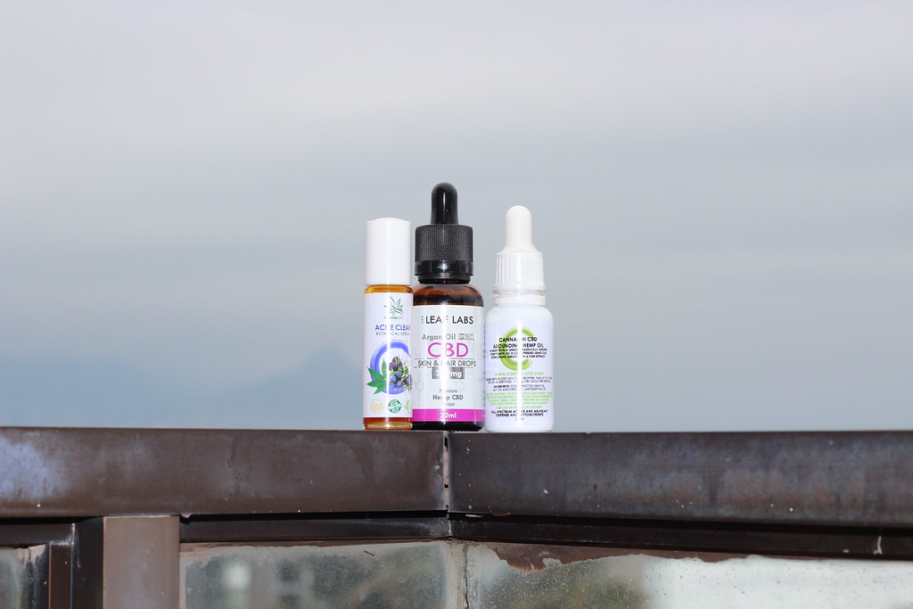 Three CBD oil bottles lined up outdoors